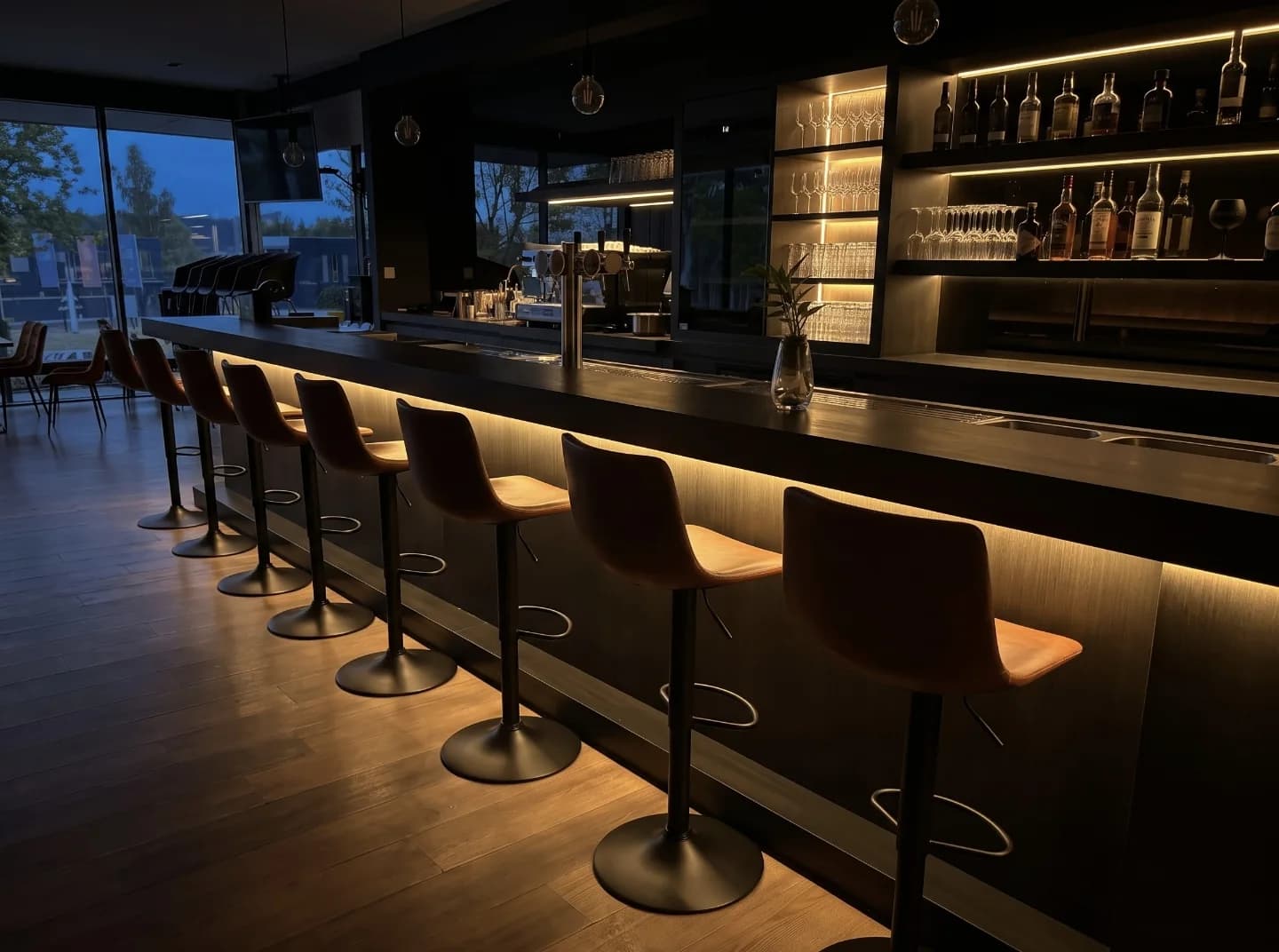 De bar met warm licht, barkrukken en verlichte flessenrekken